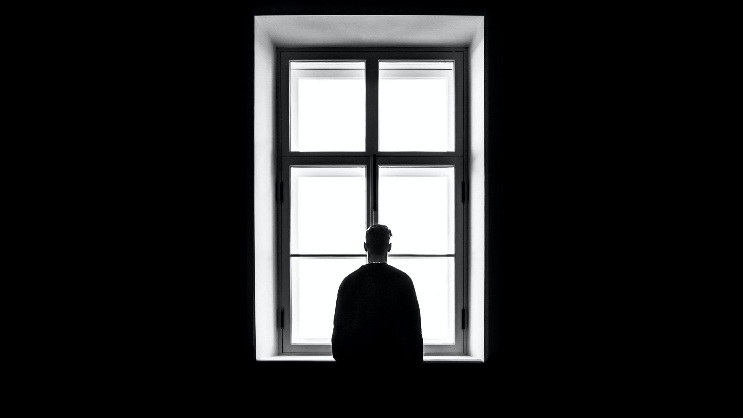 man standing at window staring deeply